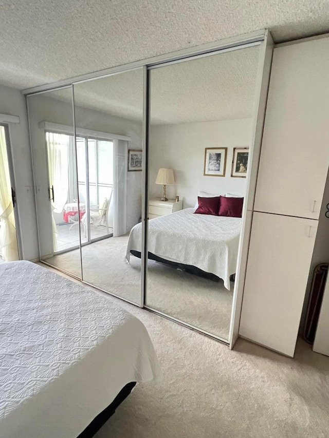 bedroom featuring a textured ceiling, light colored carpet, and a closet