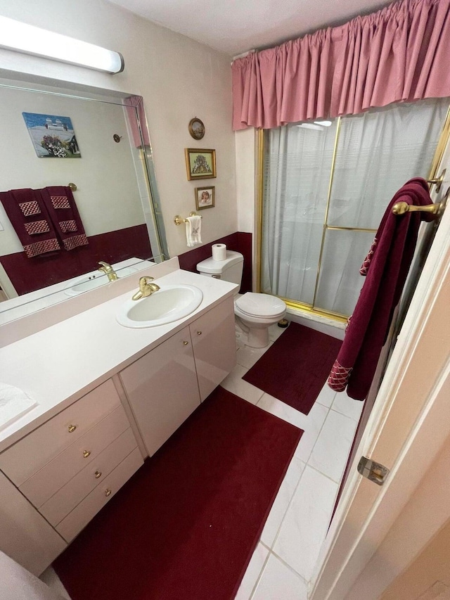 bathroom with tile patterned floors, vanity, toilet, and walk in shower