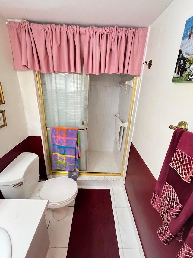 bathroom with tile patterned floors, vanity, toilet, and walk in shower