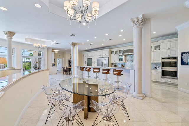 dining room with an inviting chandelier, french doors, crown molding, and decorative columns