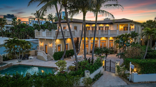 back house at dusk featuring a patio and a balcony