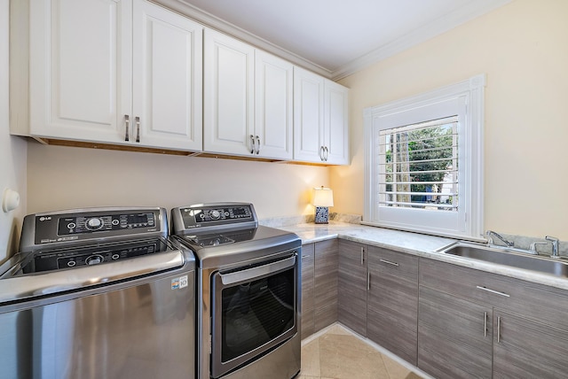 clothes washing area featuring cabinets, ornamental molding, sink, light tile patterned floors, and washing machine and dryer