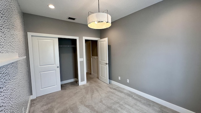 unfurnished bedroom featuring light carpet and a closet