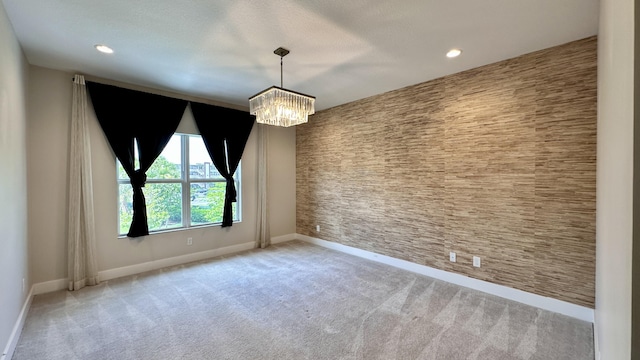 carpeted empty room featuring a chandelier