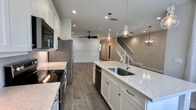 kitchen with pendant lighting, a center island with sink, sink, white cabinetry, and stainless steel appliances