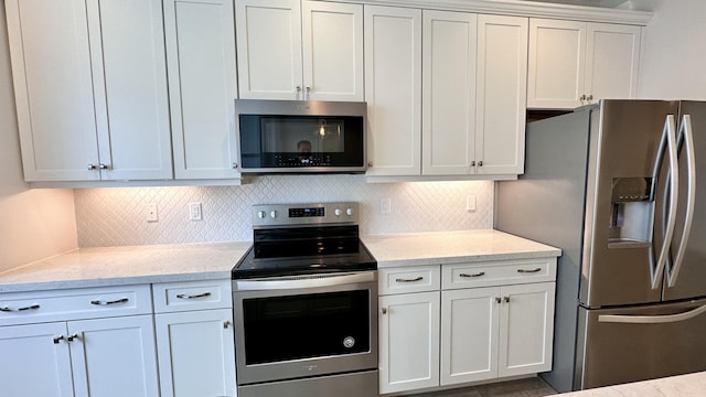 kitchen featuring tasteful backsplash, light stone counters, white cabinets, and stainless steel appliances