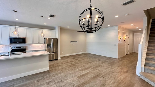 kitchen with white cabinets, decorative light fixtures, sink, and stainless steel appliances