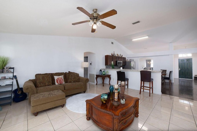 living room with ceiling fan, light tile patterned floors, and vaulted ceiling