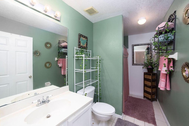 bathroom with tile patterned flooring, vanity, a textured ceiling, and toilet