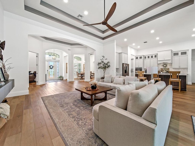 living room featuring ceiling fan, hardwood / wood-style floors, and a raised ceiling