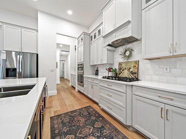 kitchen featuring light hardwood / wood-style floors, appliances with stainless steel finishes, custom exhaust hood, and tasteful backsplash