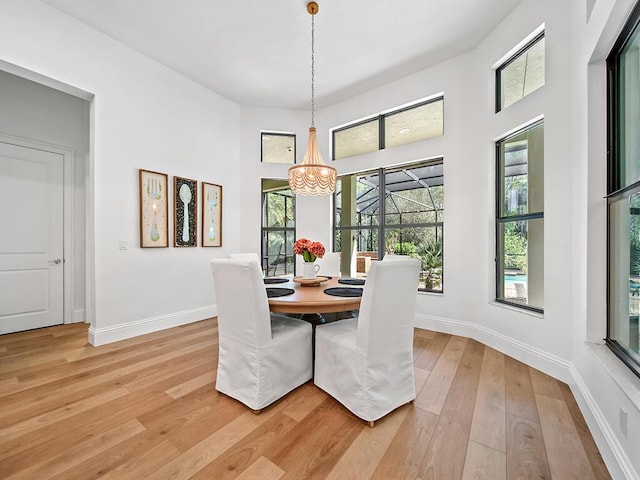 dining space featuring light wood-type flooring and a notable chandelier