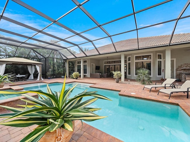 view of pool with glass enclosure, a patio area, a gazebo, and ceiling fan