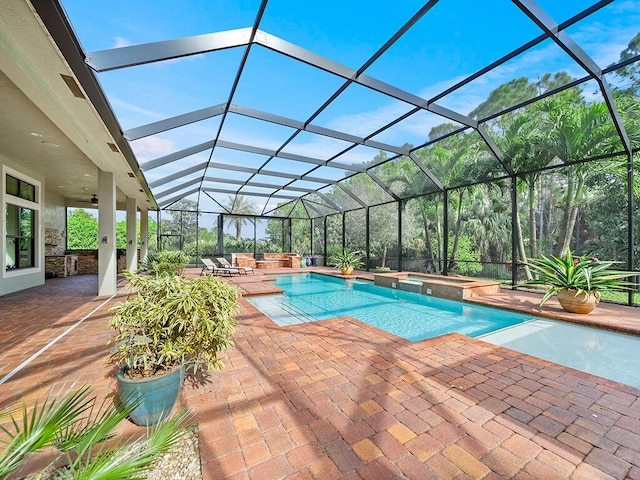 view of swimming pool featuring ceiling fan, a patio, glass enclosure, and an in ground hot tub