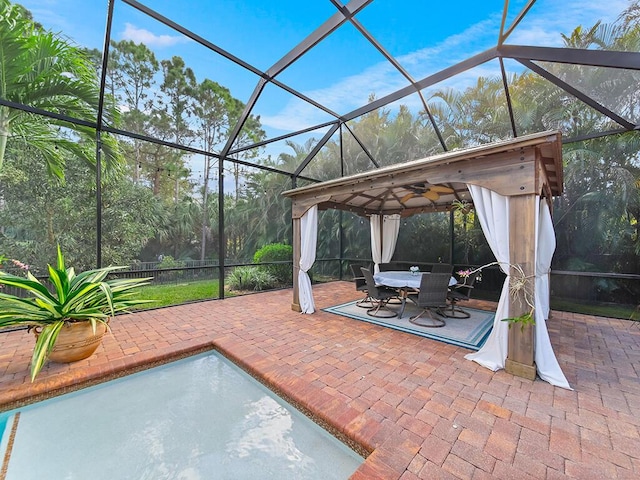 view of patio featuring ceiling fan and glass enclosure