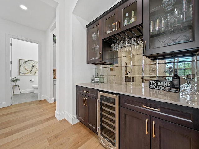 bar with wine cooler, vaulted ceiling, light hardwood / wood-style floors, decorative backsplash, and dark brown cabinetry