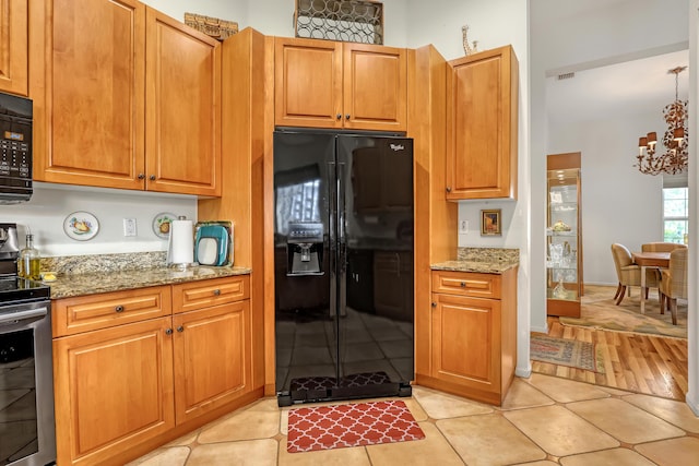 kitchen with light stone countertops, light tile patterned floors, and black appliances