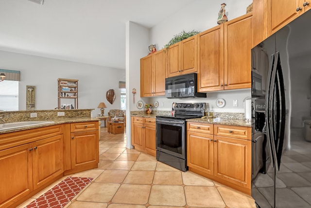 kitchen with black appliances, light tile patterned flooring, light stone counters, and sink