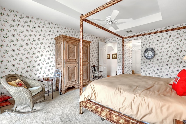 carpeted bedroom with ceiling fan and a tray ceiling