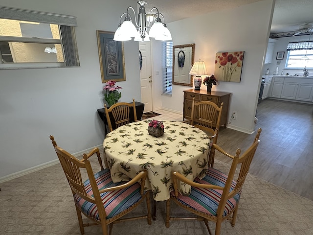 dining area with wood-type flooring, sink, and an inviting chandelier