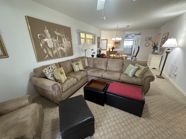 carpeted living room featuring ceiling fan with notable chandelier and a textured ceiling