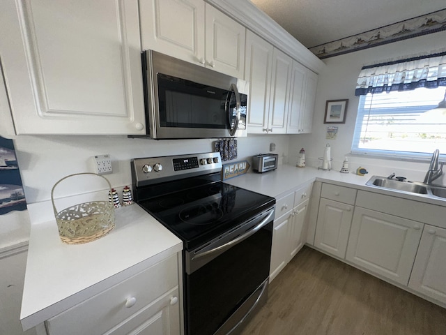 kitchen featuring white cabinets, hardwood / wood-style flooring, sink, and appliances with stainless steel finishes