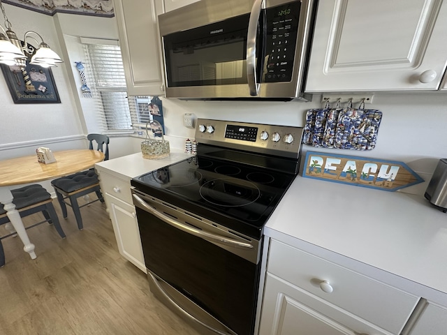 kitchen featuring white cabinets, stainless steel appliances, and light wood-type flooring