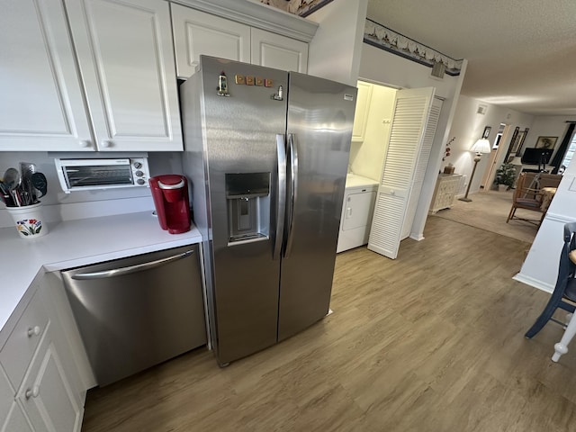 kitchen with appliances with stainless steel finishes, a textured ceiling, light hardwood / wood-style flooring, white cabinets, and washer / dryer