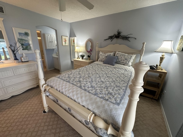 carpeted bedroom with a textured ceiling, ensuite bathroom, and ceiling fan