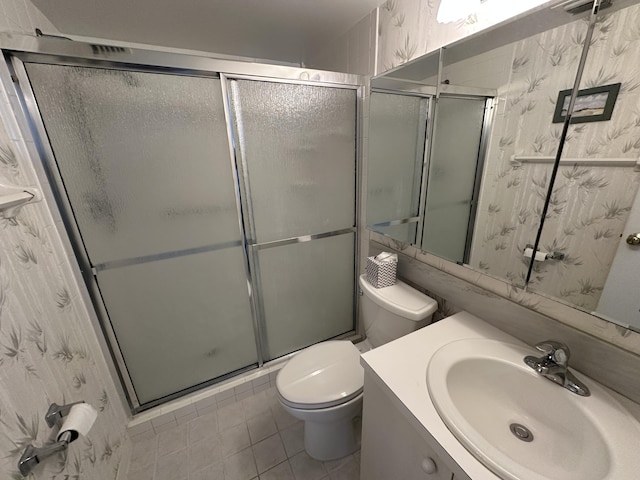 bathroom featuring tile patterned flooring, vanity, a shower with shower door, and toilet