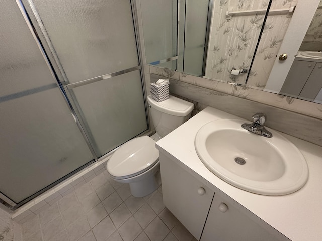 bathroom with tile patterned flooring, vanity, a shower with door, and toilet