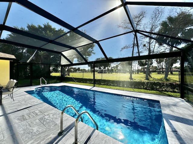 view of pool featuring a lawn, glass enclosure, and a patio area