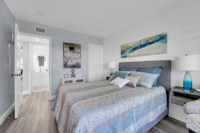 bedroom with wood-type flooring and ensuite bath