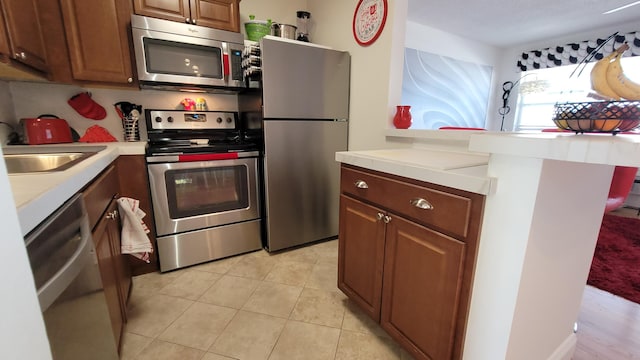 kitchen with light tile patterned floors, stainless steel appliances, and sink