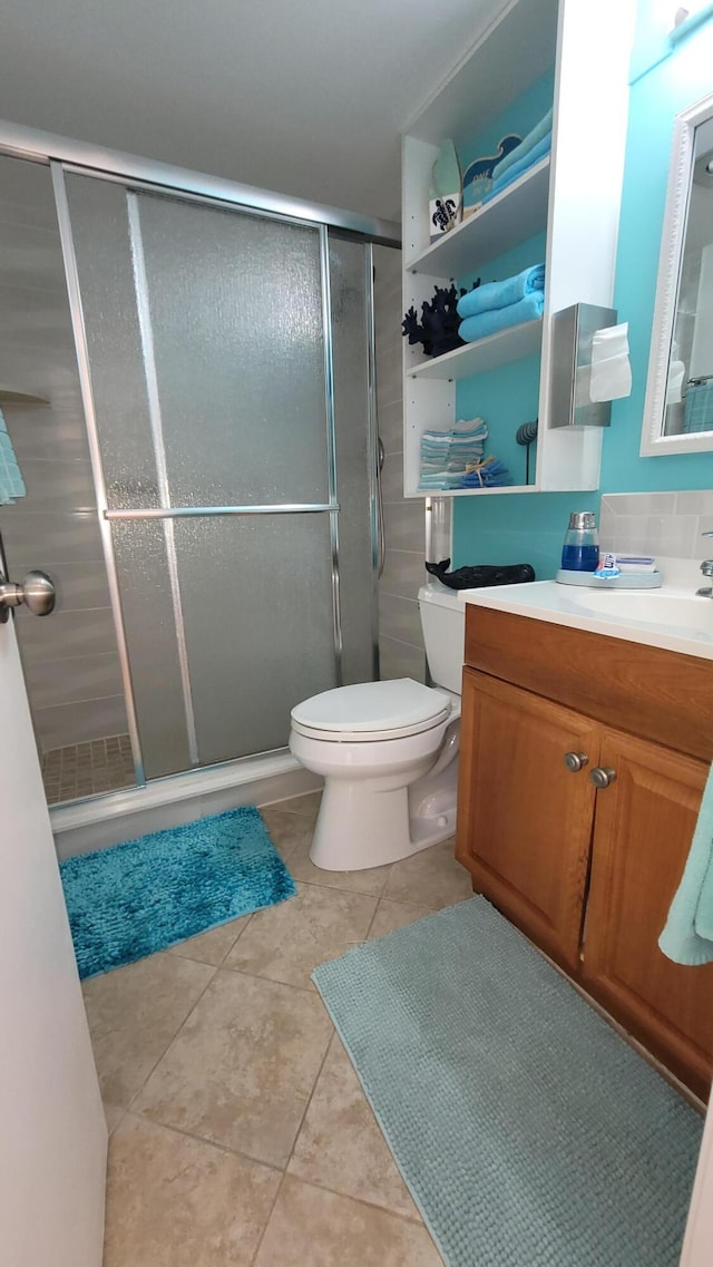 bathroom with tile patterned flooring, vanity, toilet, and an enclosed shower