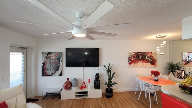 living room with ceiling fan, a textured ceiling, and hardwood / wood-style flooring