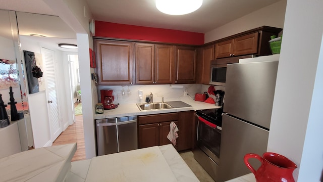 kitchen featuring dark brown cabinetry, sink, stainless steel appliances, decorative backsplash, and light wood-type flooring