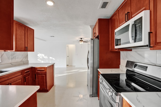 kitchen with stainless steel appliances, light stone countertops, ceiling fan, a textured ceiling, and backsplash