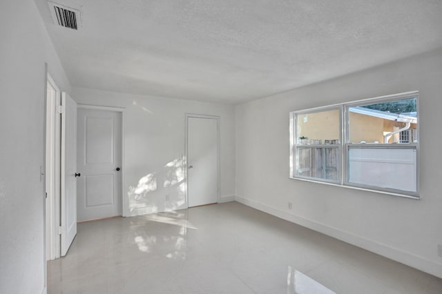 unfurnished room with a textured ceiling