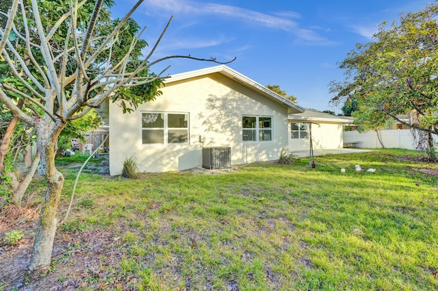 rear view of property with a yard and central air condition unit