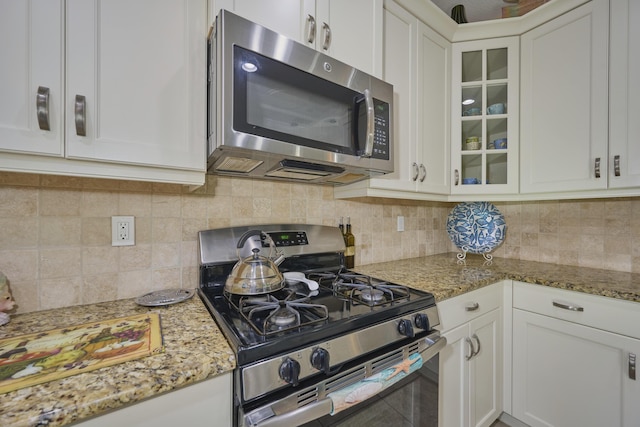 kitchen with white cabinetry, glass insert cabinets, tasteful backsplash, and appliances with stainless steel finishes