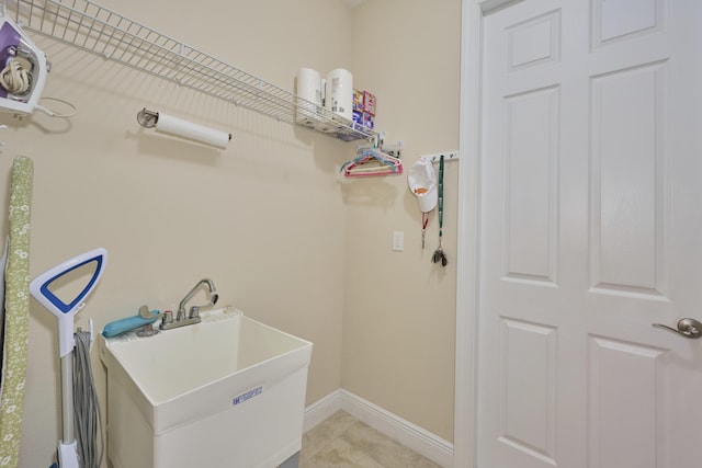 laundry room with light tile patterned flooring, a sink, and baseboards