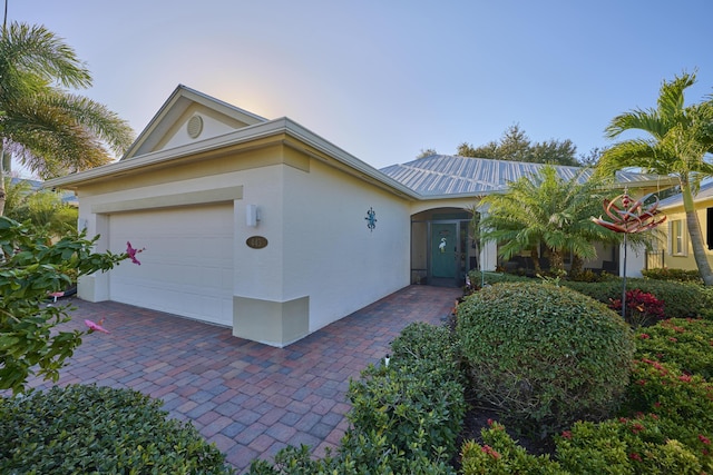 ranch-style house featuring metal roof, a garage, and stucco siding