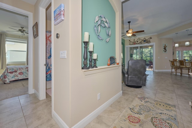 hallway with tile patterned flooring, baseboards, and crown molding