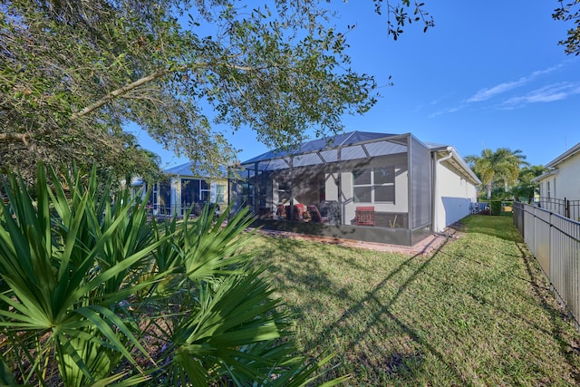 back of house featuring glass enclosure, a fenced backyard, stucco siding, and a yard