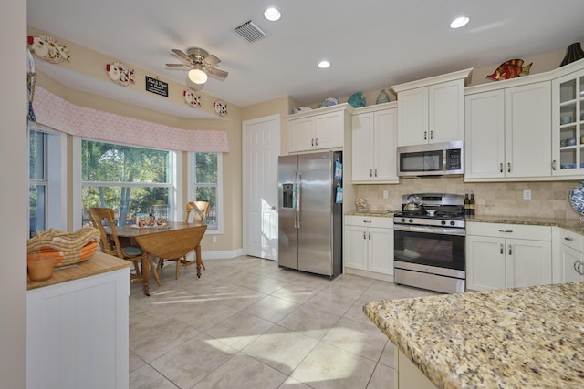 kitchen with tasteful backsplash, visible vents, light stone counters, stainless steel appliances, and white cabinetry