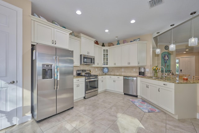 kitchen featuring visible vents, backsplash, appliances with stainless steel finishes, light stone countertops, and a peninsula