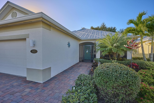 entrance to property featuring an attached garage and stucco siding