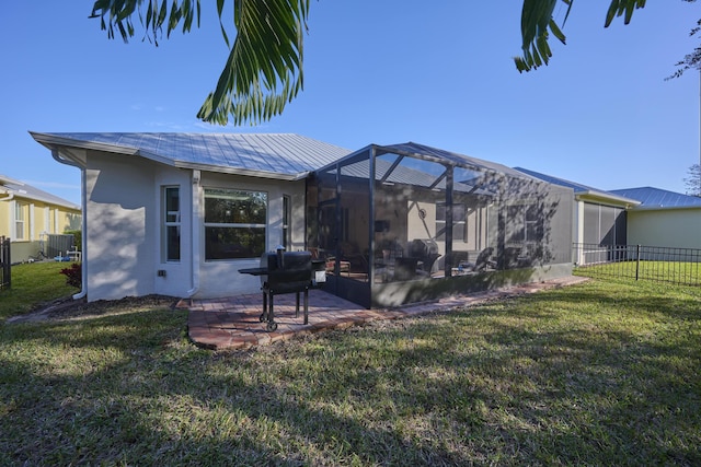 rear view of property with metal roof, glass enclosure, fence, a lawn, and a patio area