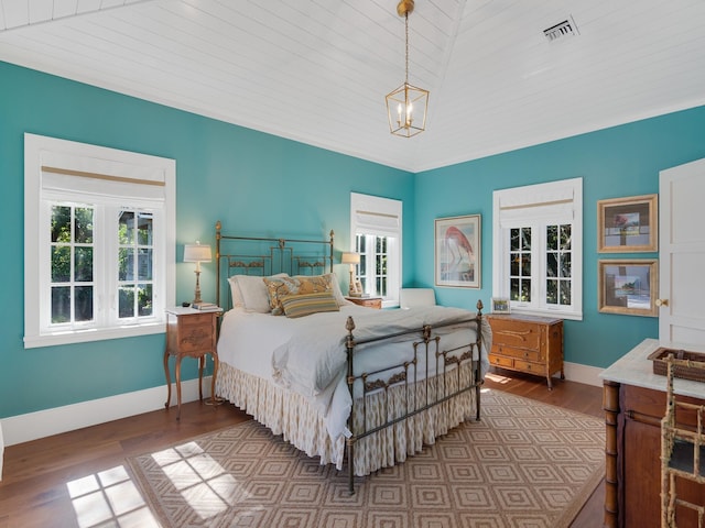 bedroom with hardwood / wood-style floors, wooden ceiling, vaulted ceiling, and an inviting chandelier